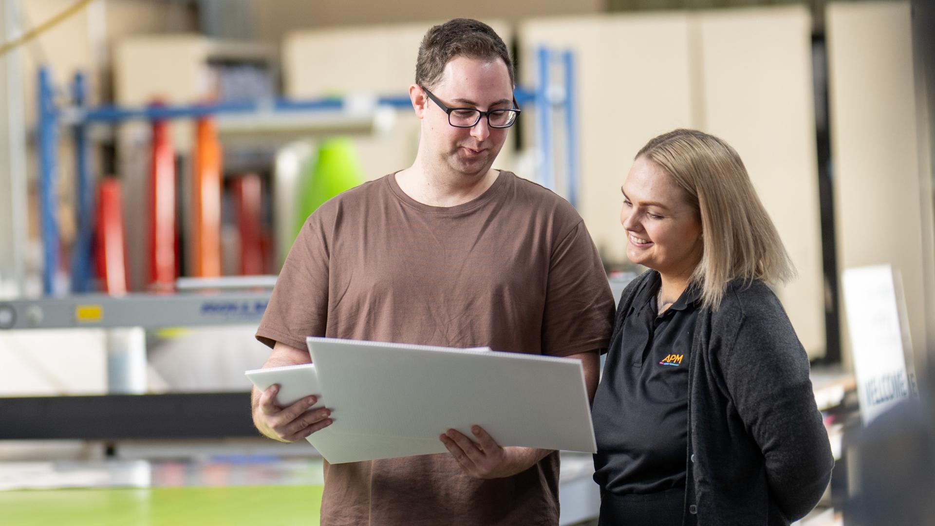 Employee with disability shows his work to an APM consultant